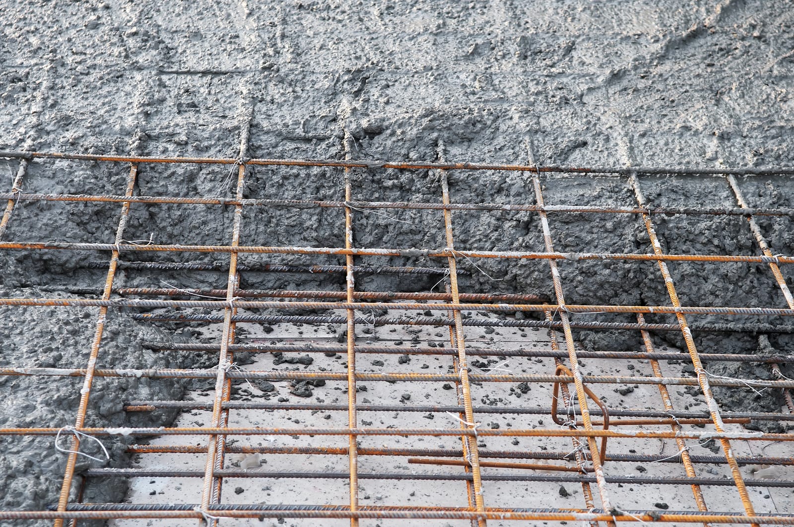Siatka zbrojeniowa z prętów stalowych w świeżo wylanym betonie fundamentu — zbrojenie ławy fundamentowej przygotowane pod beton klasy C20/25